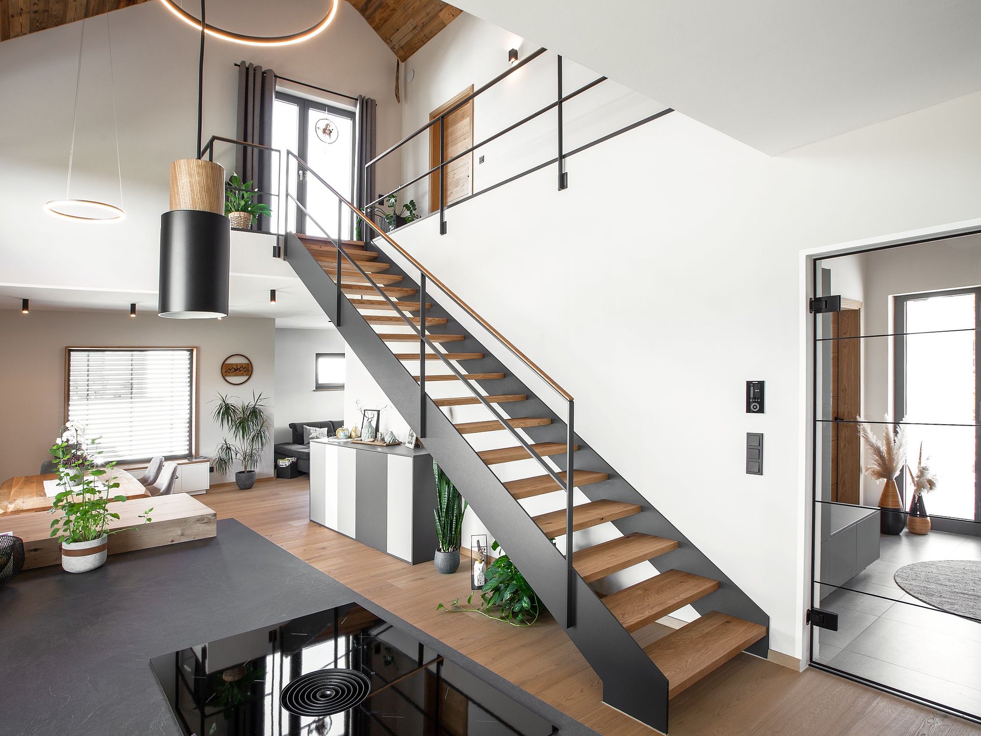 Moderne HPL-Treppe mit anthrazitfarbener HPL-Wange, massiven Eichenstufen und filigranem Stahlgeländer. Die geradlinige Konstruktion verbindet Wohn- und Galerieebene in einem offen gestalteten Einfamilienhaus.