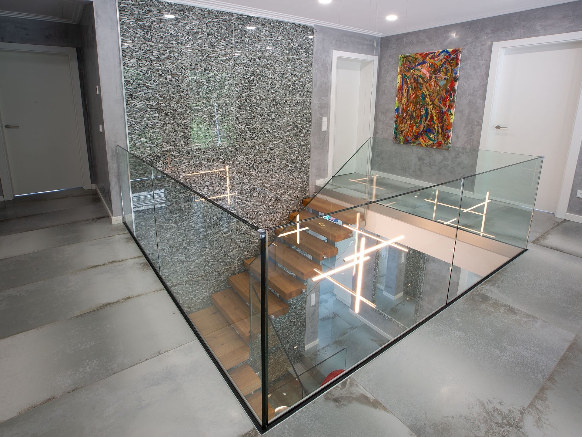 treppenoeffnung-moderner-wohnraum.jpg Glasgeländer an einer offenen Treppenanlage Großflächiges transparentes Glasgeländer sichert die Treppenöffnung einer modernen Treppenanlage mit Holzstufen und verbindet die beiden Wohnebenen optisch miteinander.