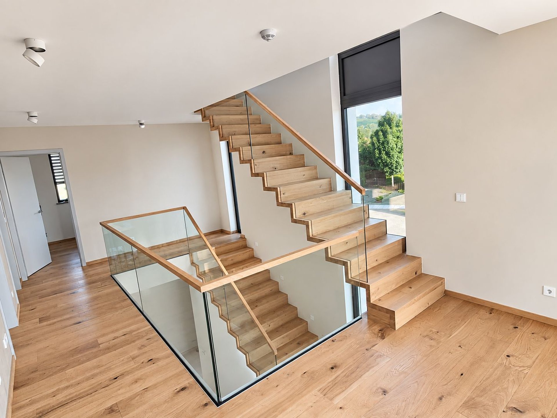 Faltwerktreppe über zwei Etagen mit Glasgeländer und Handlauf aus Holz Faltwerktreppe über zwei Etagen mit Glasgeländer und Handlauf aus Holz