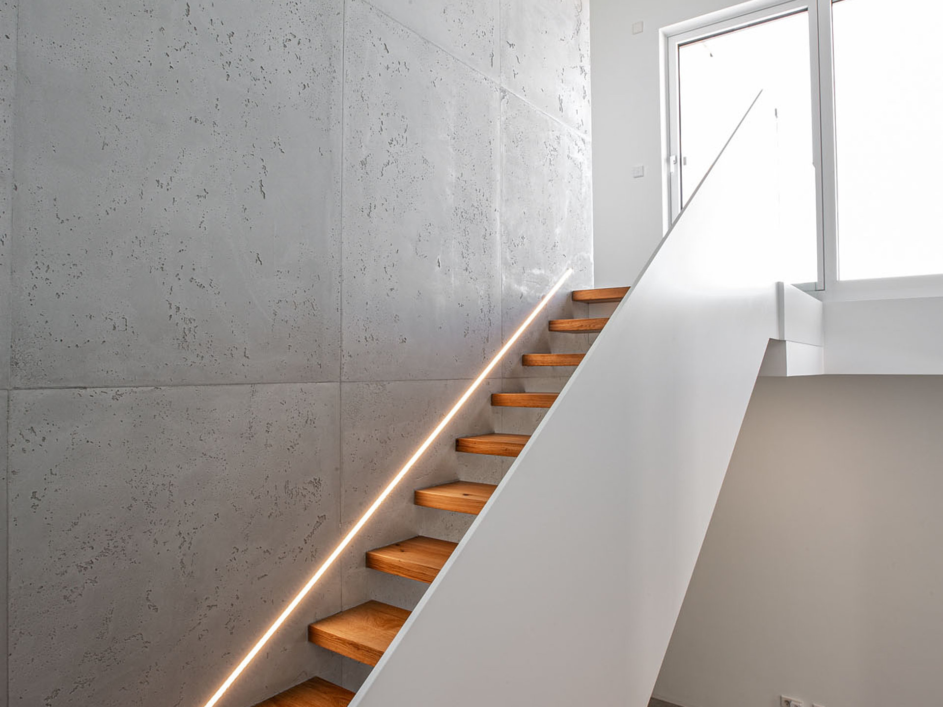 Gebolzte Treppe in Asteiche mit Wandbeleuchtung und weißem Geländer von Krieger-Treppen