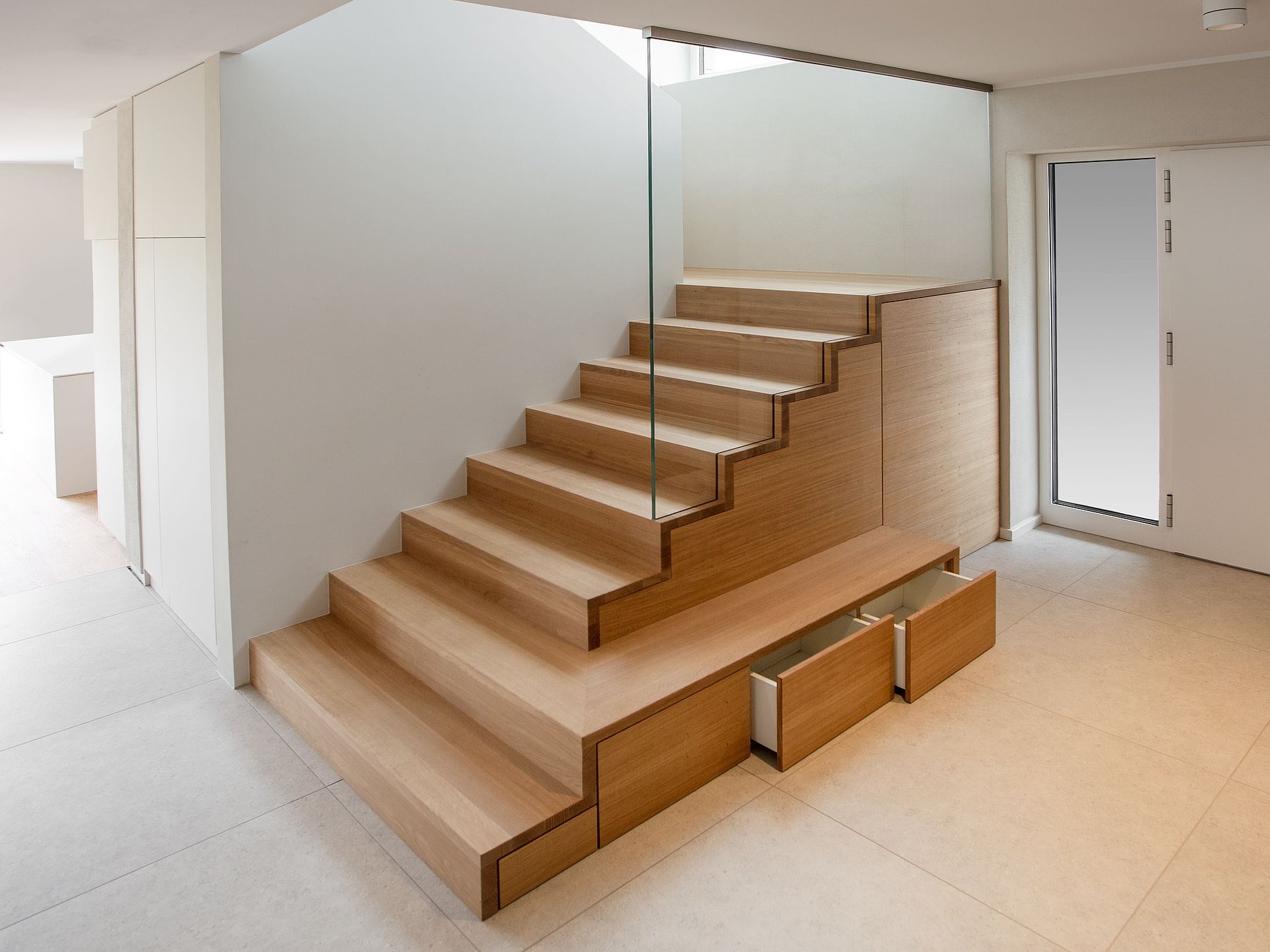 Holztreppe mit Treppenschrank und geöffneten Schubladen im unteren Treppenbereich zur platzsparenden Nutzung des Raums unter der Treppe.