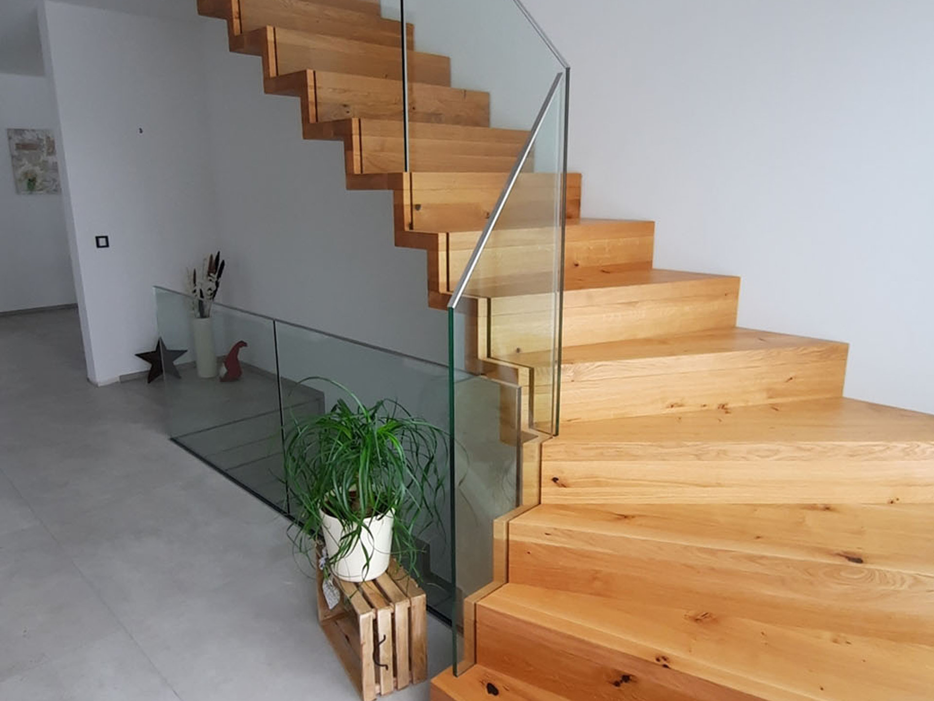 Gewendelte Holztreppe in Faltwerkoptik und eingespanntem Glas