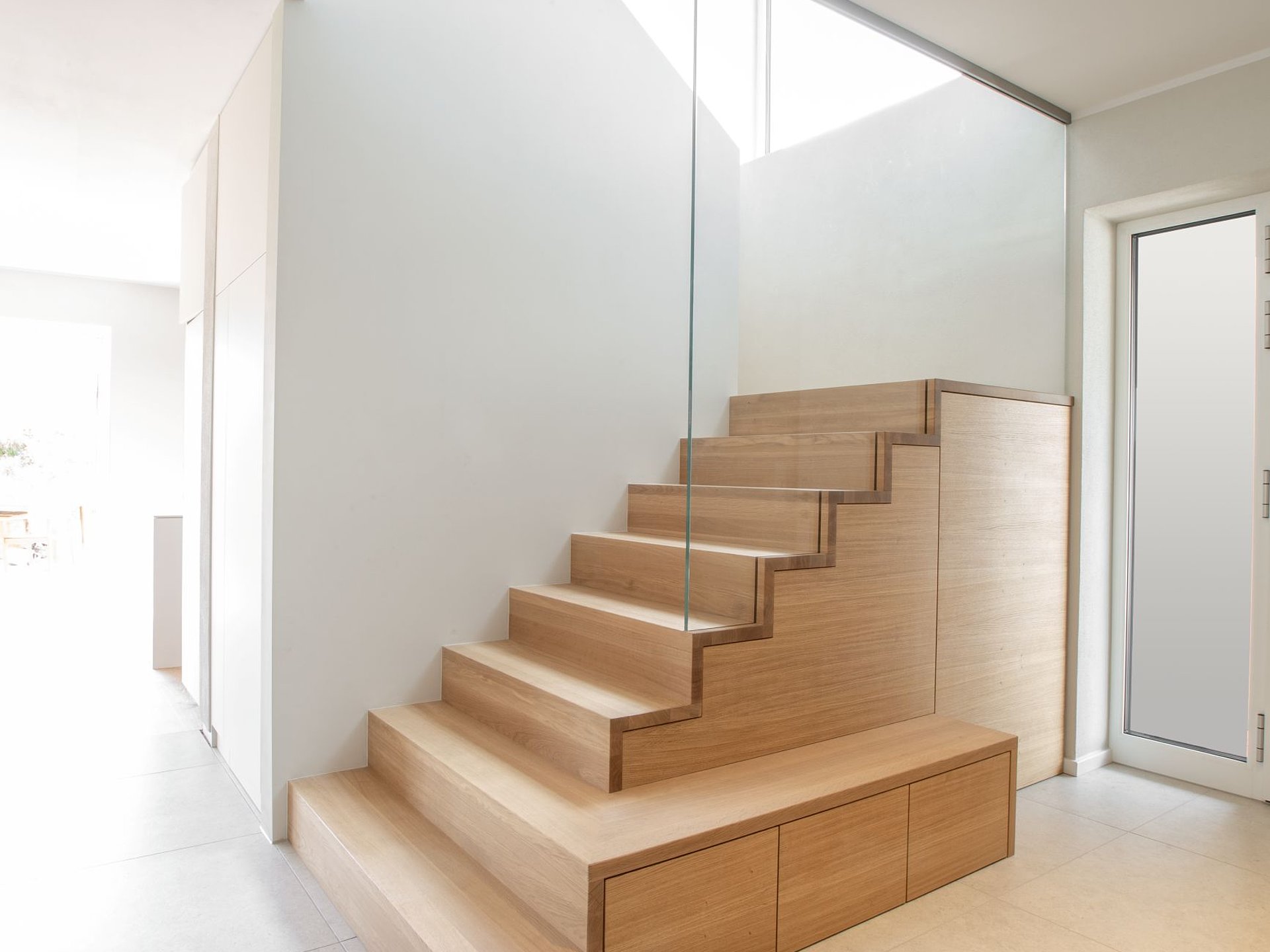Geschlossene Schranktreppe aus Holz mit passgenau in den Treppenunterbau integrierten Schrankelementen und Schubladen.