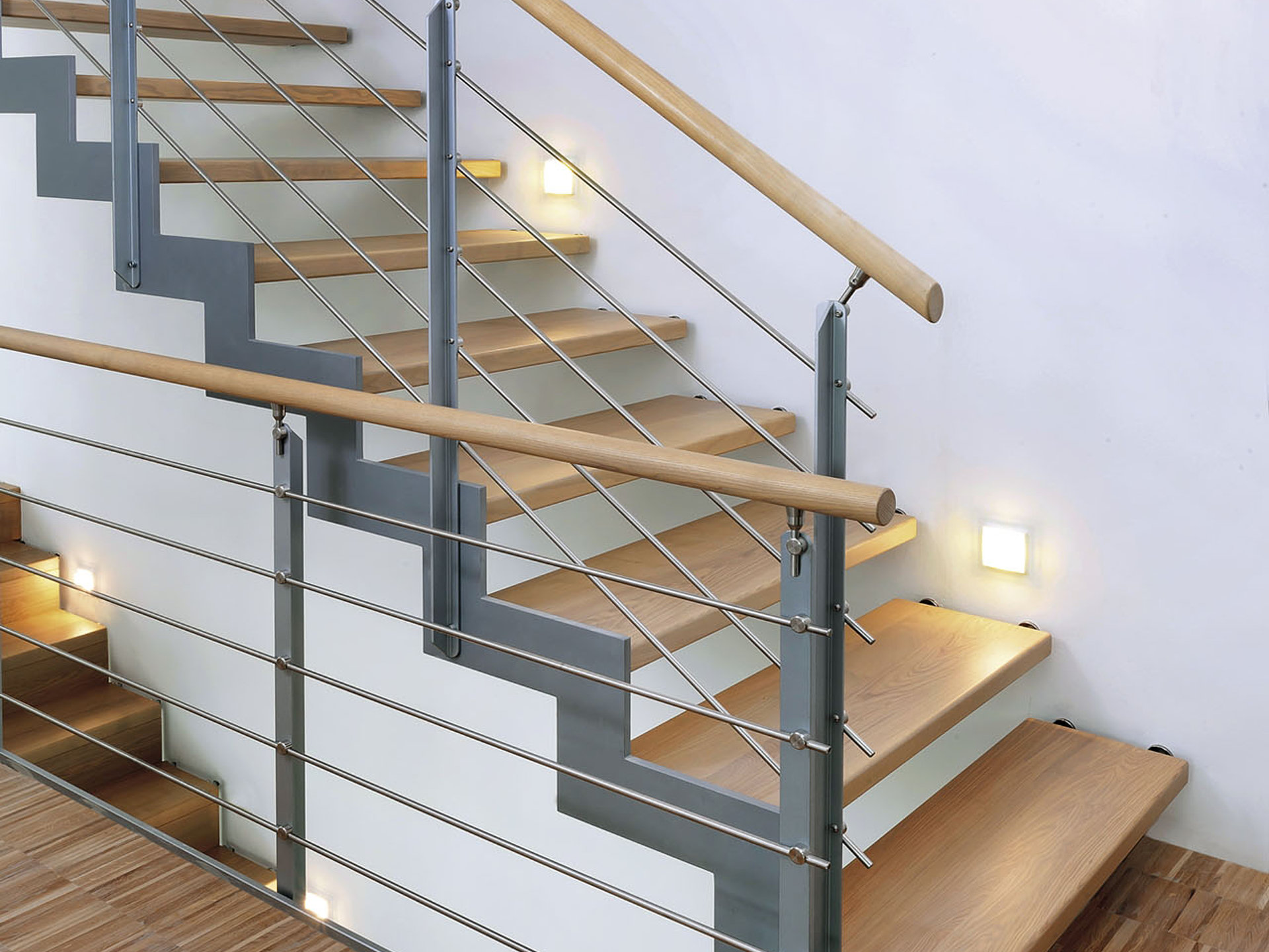 Wandgelagerte Stahltreppe mit Eichestufen und Relinggeländer