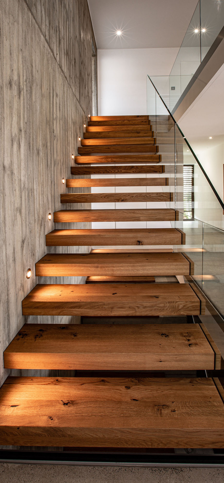 Beleuchtete Kragstufentreppe mit Ganzglasgeländer von Krieger-Treppen