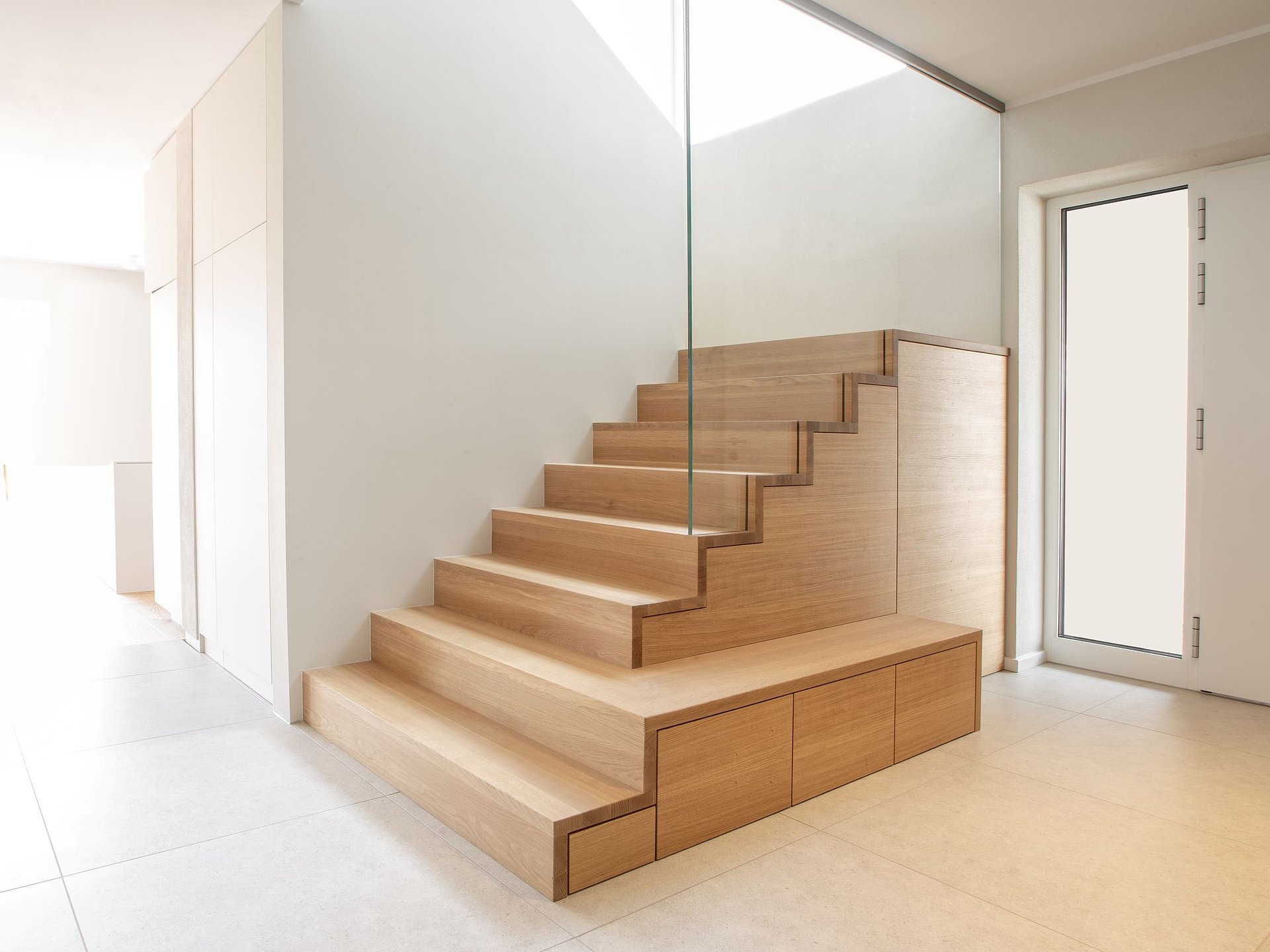 Seitliche Ansicht eines Treppenschranks aus Holz, dessen Schrankfronten dem stufenförmigen Verlauf der Treppe folgen und zusätzlichen Stauraum schaffen.